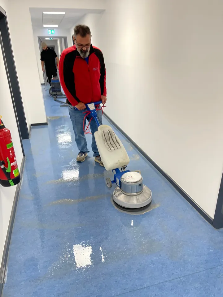 Bodengrundreinigung mit der Einscheibenmaschine in einem Flur mit blauem Linoleumboden