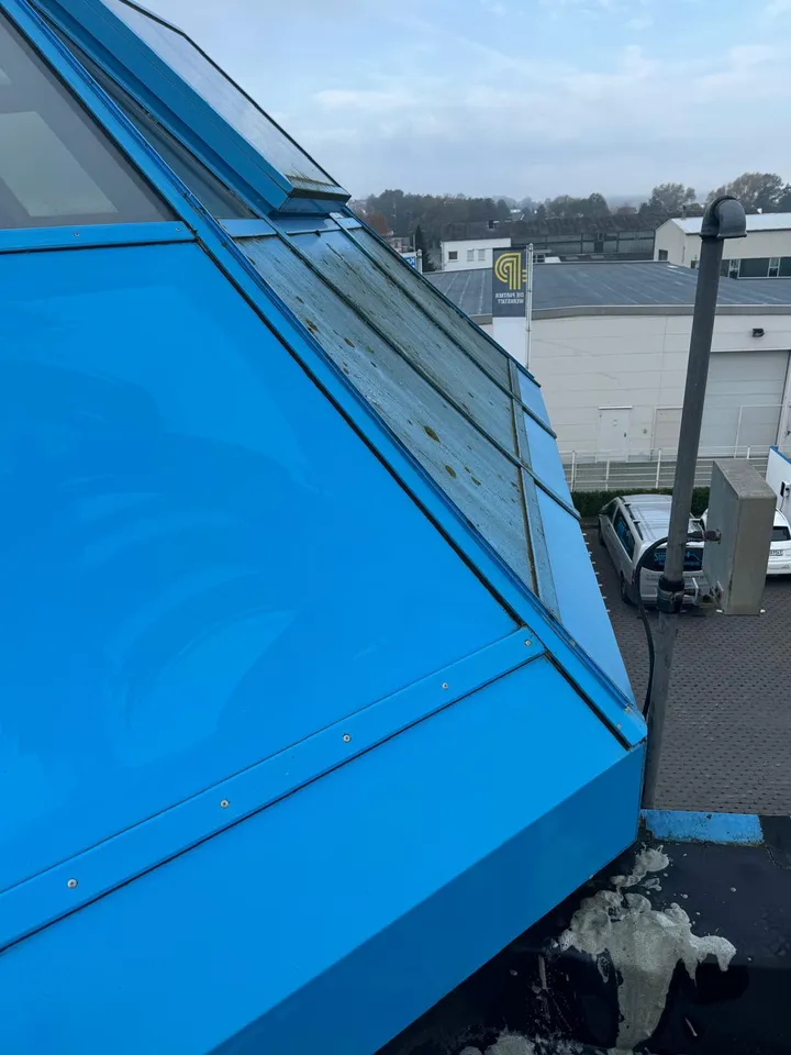 Blau verkleideter Dachaufbau während der Reinigung — die linke Seite ist bereits sauber, rechts noch Belag
