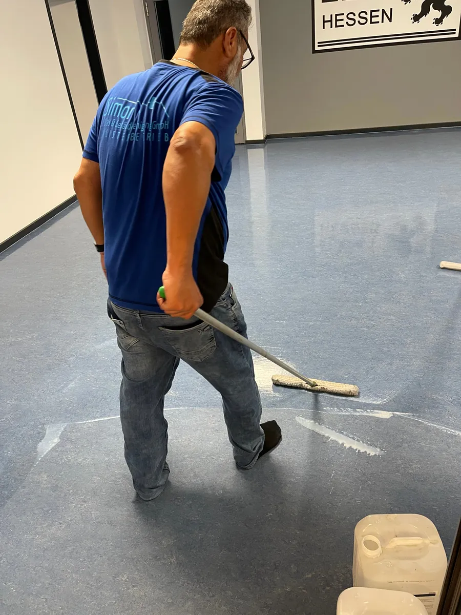 Mitarbeiter im Simon-Firmenshirt beim Beschichten eines frisch gereinigten Bodens
